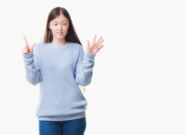 Gösterilen ve parmakları ile işaret izole arka plan üzerinde Genç Çinli kadın kendinden emin ve mutlu gülümseyerek süre yedi numara.