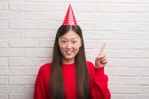 Jovem Chinesa Sobre Parede Tijolo Usando Chapéu Aniversário Surpreso Com — Fotografia de Stock