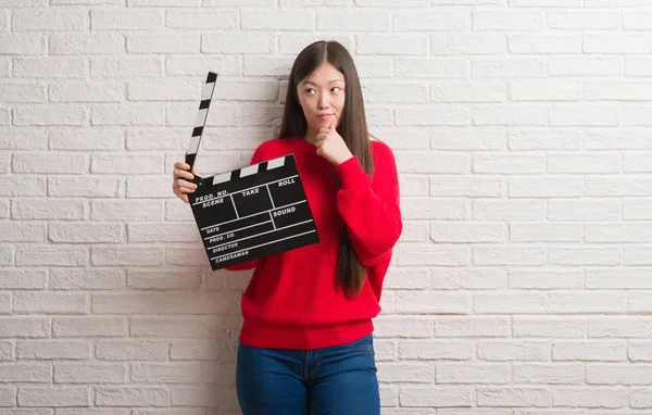 Fıçı tahtası ciddi bir yüz düşünme hakkında soru, çok karışık fikir holding beyaz tuğla duvarın üzerinden Genç Çinli kadın