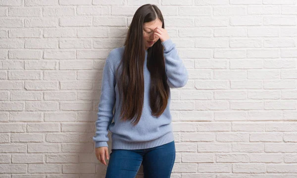 Genç Chinise kadın beyaz tuğla duvar sürtünme burun ve göz yorgunluğu ve baş ağrısı duygu yorgun. Stres ve hayal kırıklığı kavramı.