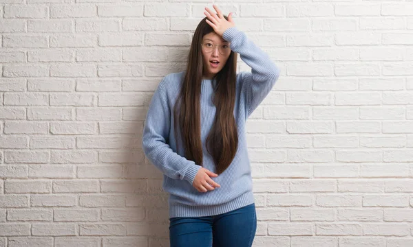 Genç Chinise kadın beyaz tuğla duvar başında hata için el ile sürpriz hata hatırlıyorum. Unuttum, kötü bellek kavramı.