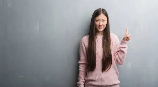 Jonge Chinese Vrouw Grijs Muur Tonen Omhoog Met Vinger Nummer — Stockfoto