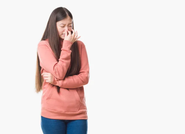 年轻的中国妇女在被隔绝的背景穿着体育 Sweathshirt 嗅到的东西臭味和恶心 无法忍受的气味 用手指在鼻子上屏住呼吸 坏气味概念 — 图库照片