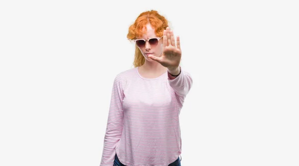 防衛ジェスチャー 深刻な自信を持って式に一時停止の標識を行うオープン手でサングラスをかけている若い赤毛の女性 — ストック写真