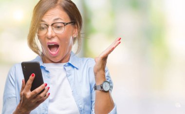 Orta yaş kadın kıdemli manifatura üzerinden Smartphone kullanarak ileti gönderme büyük gülümseme ile çığlık zaferini kutluyor ve ellerini kaldırdı arka plan çok mutlu ve heyecanlı, kazanan ifade izole