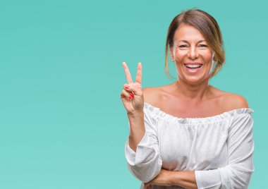 Orta yaş İspanyol kadın kıdemli mutlu yüz zafer işareti yaparken kameraya göz kırpıyor ile gülümseyen izole arka plan üzerinde. İki numaralı.