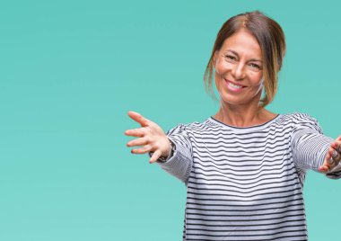 Orta yaş İspanyol kadın kıdemli sarılmak için kollarını açarak gülümseyerek kameraya bakarak izole arka plan üzerinde. Neşeli ifade kucaklayan mutluluk.