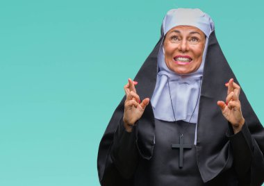 Orta yaş üst düzey Hıristiyan Katolik Rahibe kadın geçiş parmakları umut ve gözler gülümseyen izole arka plan yüzünden kapalı. Şans ve batıl kavramı.
