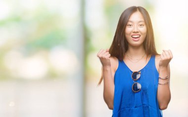 Genç Asyalı kadın kutluyor izole arka plan üzerinde şaşırttı ve başarı için kaldırdı kollarını açarak hayret ve gözleri açık. Kazanan kavramı.