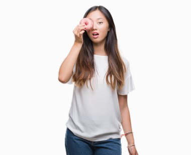 Genç Asyalı kadın izole arka şok sürpriz yüzü, korkuyor ve korku ifadesi ile heyecanlı olan korkmuş üzerinden donut yemek