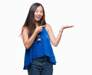 Genç Asyalı kadın üzerinden hayran ve el ile sunulması ve parmak ile işaret ederken kameraya gülümseyen izole arka plan.