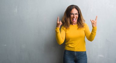 Orta yaş İspanyol kadın deli ifade rock simge elle yapıyor ile bağırarak gözlüklü gri duvar yüzünden. Müzik yıldızı. Ağır kavramı.