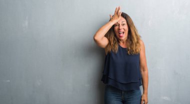 Gri grunge duvar başında hata için el ile sürpriz üzerinde duran orta yaş İspanyol kadın hata hatırlıyorum. Unuttum, kötü bellek kavramı.