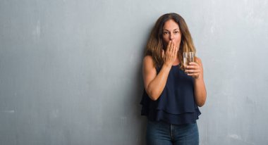 Orta yaş İspanyol kadın su kapak ağız el için hata, ifade korku, utanç ile şok ile bardak içme sessizlik içinde gizli kavramı korkuttu