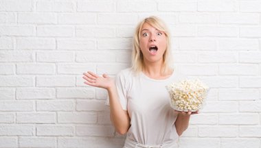 Çok mutlu ve heyecanlı, pop Mısır yeme beyaz tuğla duvar büyük gülümseme ile çığlık ve ellerini kaldırdı kazanan ifade kutluyor zafer yetişkin beyaz kadın