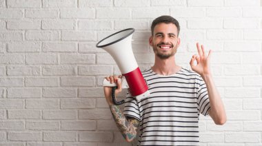 Parmak, mükemmel sembolü ile ok işareti yapıyor megafon tutan genç yetişkin adam