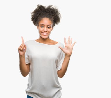 Genç afro Amerikan kadın gösterilen ve parmakları ile işaret izole arka plan yüzünden kendinden emin ve mutlu gülümseyerek süre 6 numara.