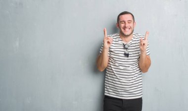 Beyaz delikanlı geçiş parmakları umut ve gözleri kapalı ile gülümseyen gri grunge duvarın üzerinden. Şans ve batıl kavramı.