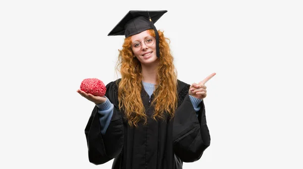 Giovane Rossa Studentessa Con Indosso Uniforme Graduata Tenendo Cervello Molto — Foto Stock