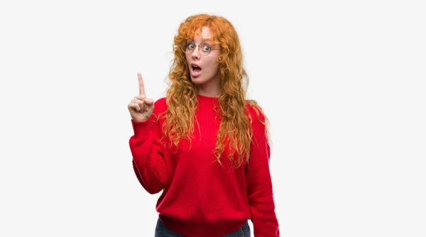 成功したアイデアを赤いセーター人差し指を着て若い赤毛の女性 終了したと満足しています ナンバーワン — ストック写真