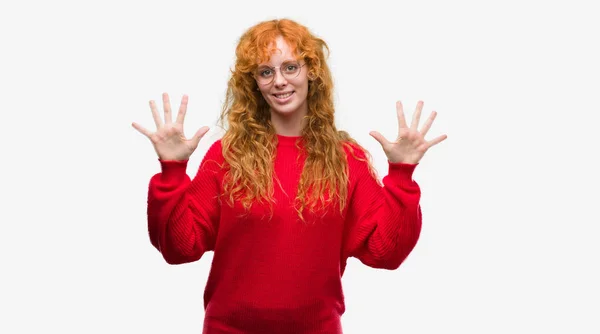 指で上向きの表示と赤いセーターを着ている若い赤毛の女性数は自信を持って 幸せな笑みを浮かべている間 — ストック写真
