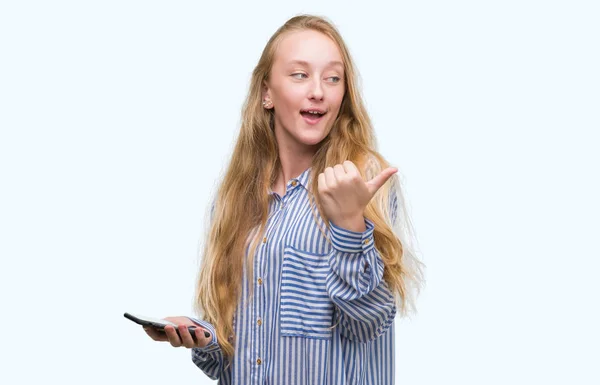 Blonde Teenager Frau Mit Smartphone Zeigt Mit Dem Daumen Zur — Stockfoto