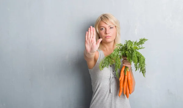 Kaukasiska Vuxen Kvinna Över Grå Grunge Väggen Håller Färska Morötter — Stockfoto