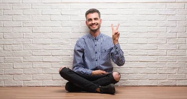 Νεαρός Ενήλικος Άνδρας Κάθεται Πάνω Στον Τοίχο Λευκό Χαμογελώντας Χαρούμενο — Φωτογραφία Αρχείου