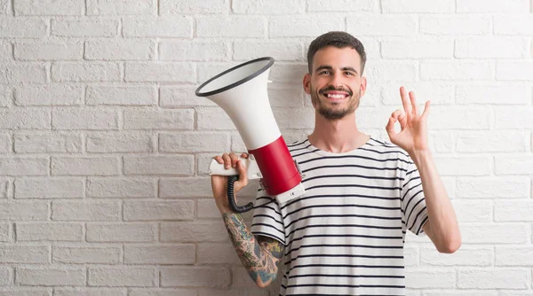 Parmak, mükemmel sembolü ile ok işareti yapıyor megafon tutan genç yetişkin adam