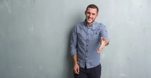 Joven Hombre Caucásico Sobre Gris Pared Grunge Sonriendo Amistoso Ofreciendo —  Fotos de Stock