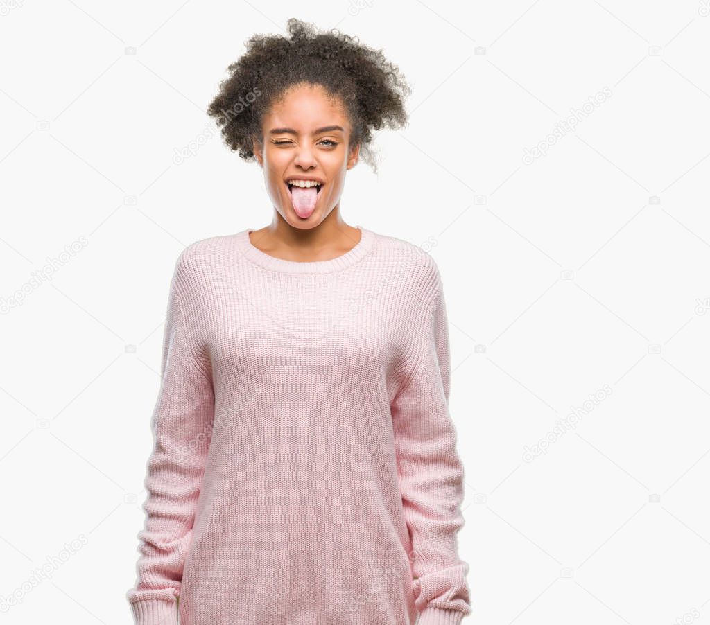 Young afro american woman wearing winter sweater over isolated background sticking tongue out happy with funny expression. Emotion concept.