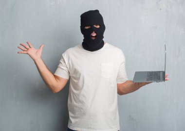 Genç beyaz hacker adam çığlık ile büyük zaferini kutluyor dizüstü çok mutlu ve heyecanlı, kazanan ifade kullanarak siber saldırı yapmak gri grunge duvarın üzerinden gülümse ve el kaldırdı