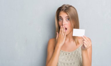 Hata, korku, sessizlik içinde gizli kavramı korkmuş ifade için utanç ile boş ziyaret kart kapağı ağız eliyle tutarak grunge gri duvar güzel genç kadın şok