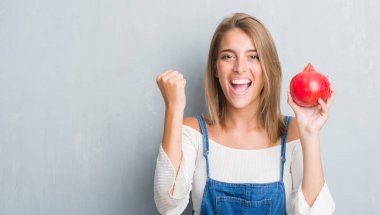 Güzel ve genç birbayan gurur çığlık ve zafer ve başarı çok heyecanlı, kutluyor nar tutan grunge gri duvarın üzerinden duygu tezahürat