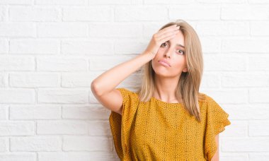 Güzel genç kadın elle kafasına, utanç ve sürpriz yüz ile şok vurguladı beyaz tuğla duvarın üzerinden öfkeli ve sinirli. Korku ve hata için üzgün.