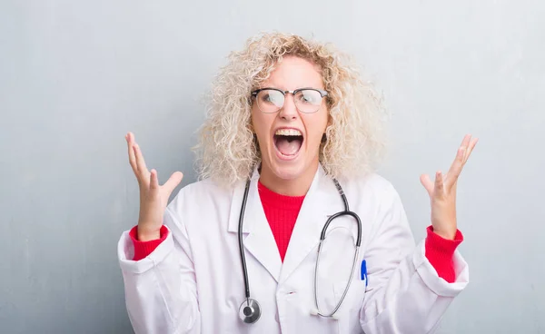 Joven Doctora Rubia Sobre Pared Gris Grunge Celebrando Loca Sorprendida —  Fotos de Stock