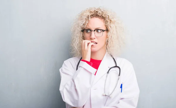 Joven Doctora Rubia Sobre Pared Gris Grunge Mirando Estresada Nerviosa —  Fotos de Stock