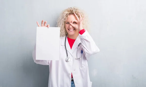 Jonge Blonde Dokter Vrouw Grunge Grijs Muur Met Blanco Papier — Stockfoto