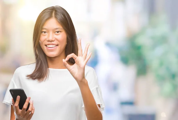Młoda Kobieta Azjatyckich Sms Pomocą Smartfona Białym Tle Robi Znak — Zdjęcie stockowe