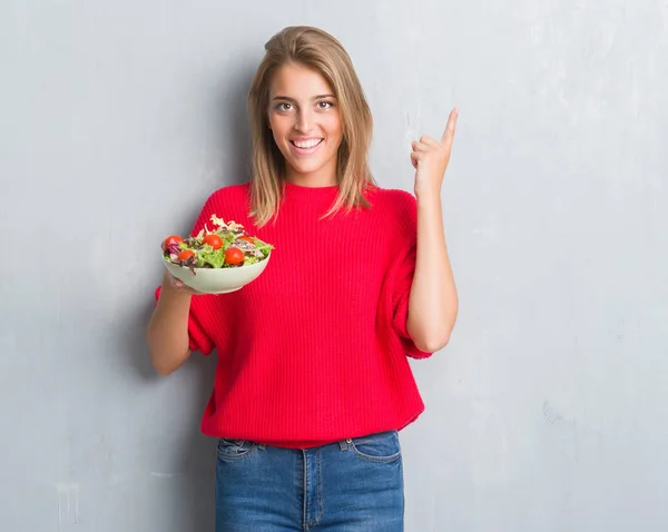 Mulher Bonita Sobre Grunge Parede Cinza Comendo Salada Tomate Surpreso — Fotografia de Stock