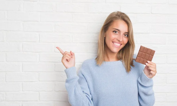 Hermosa Mujer Joven Sobre Pared Ladrillo Blanco Comer Barra Chocolate —  Fotos de Stock