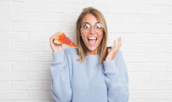 ピザを食べる白いレンガの壁に美しい若い女性が笑顔で叫んで勝利を祝って非常に幸せと興奮 受賞式をスライスし 手を上げた — ストック写真