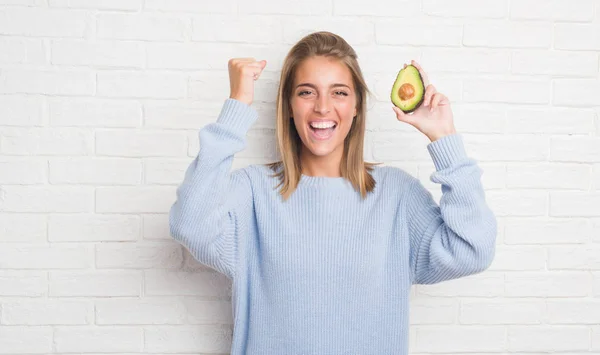 Beautiful Young Woman White Brick Wall Eating Fresh Avocado Screaming — Stock Photo, Image