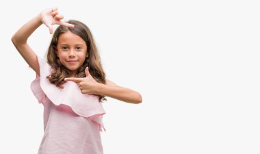 Elle yapma çerçeve ve parmakları ile mutlu yüz gülümseyen pembe elbise esmer İspanyol kız. Yaratıcılık ve Fotoğrafçılık kavramı.