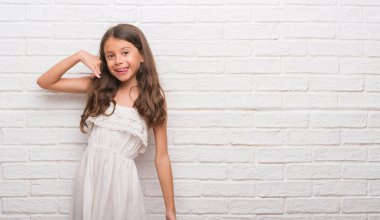 Üzerinde beyaz tuğla duvar gülümseyen genç İspanyol çocuğun el ve parmak telefonda konuşmak ile telefon jest yapıyor. Kavramları iletişim.