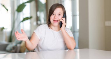 Down sendromu kadın evde kocaman bir gülümseme ile çığlık zaferini kutluyor smartphone çok mutlu ve heyecanlı, kazanan ifade kullanarak ve ellerini kaldırdı