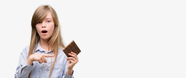 Joven Niña Rubia Sosteniendo Barra Chocolate Muy Feliz Señalando Con — Foto de Stock
