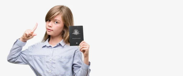 年轻的金发孩子持有澳大利亚护照惊讶于一个想法或问题指着一个快乐的脸 — 图库照片