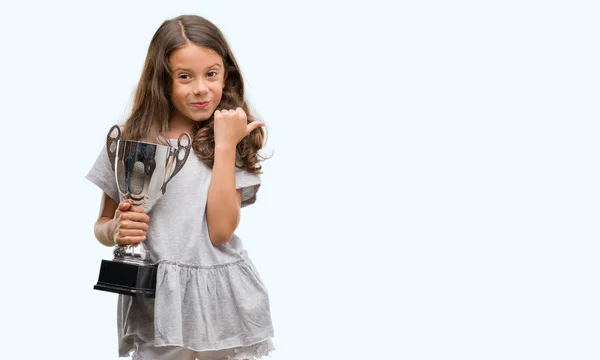 Brunette Hispanic Girl Holding Trophy Pointing Showing Thumb Side Happy — Stock Photo, Image