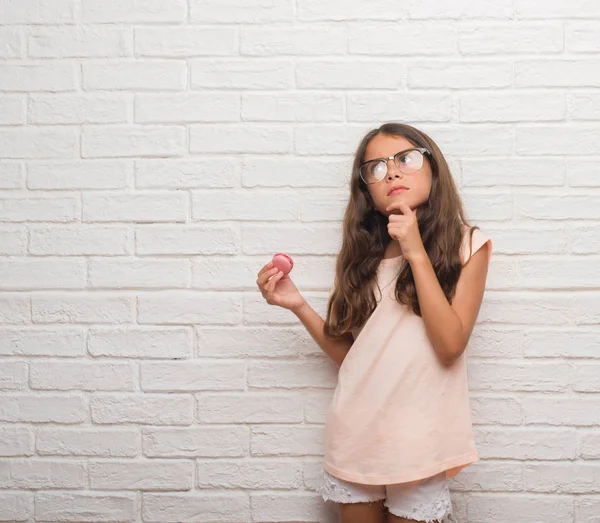 Unga Spansktalande Barn Över Vitt Tegel Vägg Ätande Rosa Macaron — Stockfoto